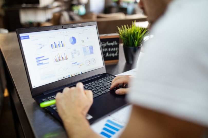 Profissionais analisando relatórios financeiros em laptop com ícone de cadeado representando segurança de dados