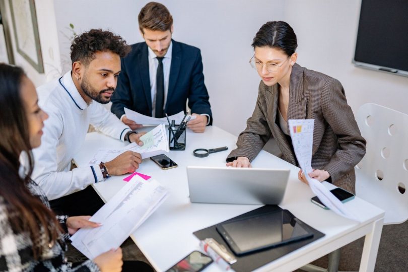 Equipe empresarial analisando documentos e relatórios de conformidade de inteligência artificial