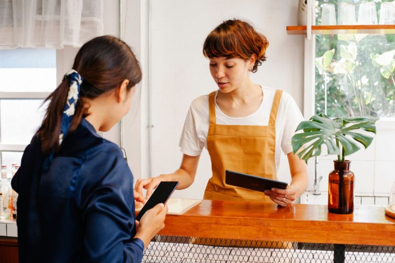 Proprietário de pequena empresa analisando interface de chatbot em smartphone para suporte via WhatsApp